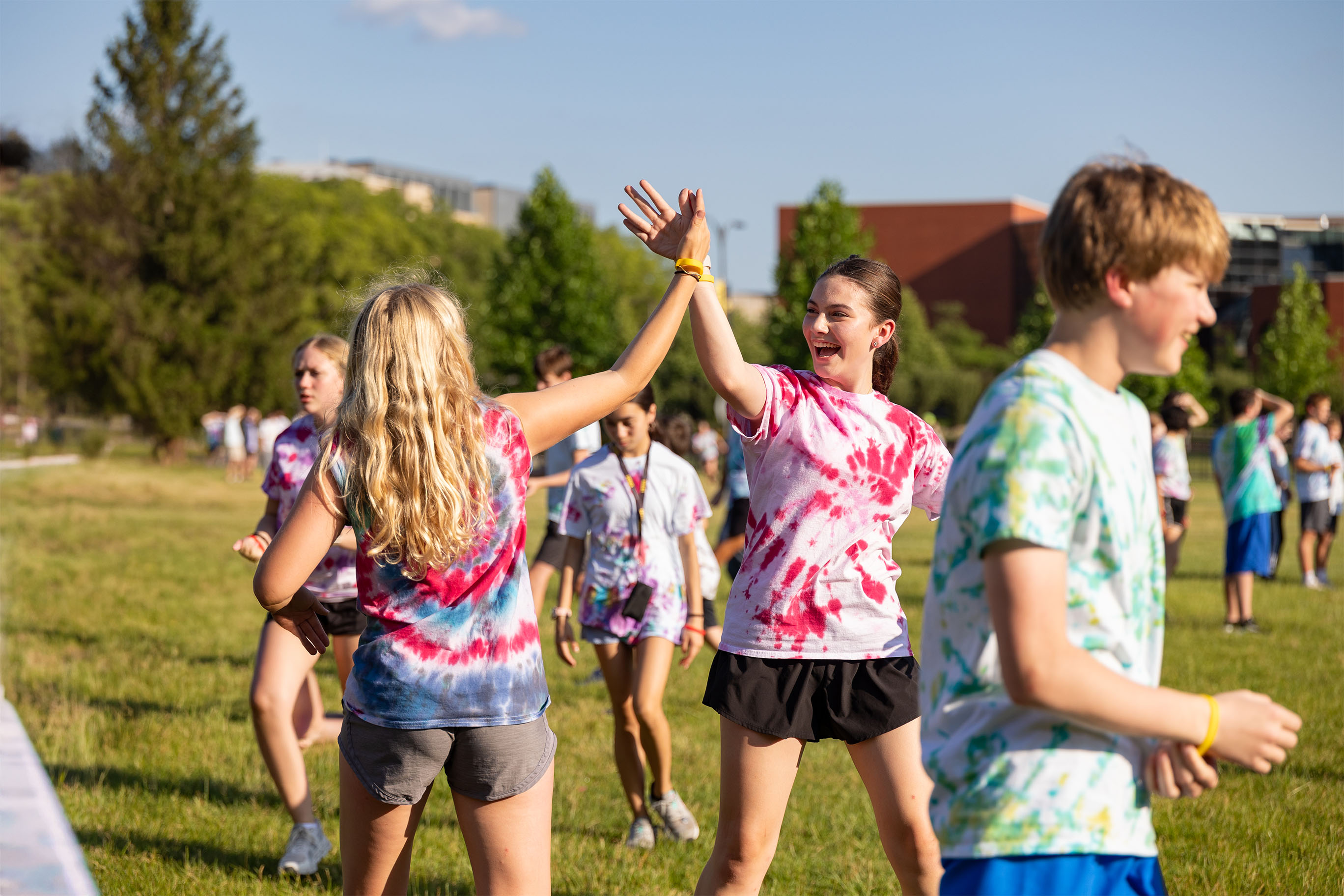 Students in tie-dye shirts high-fiving at a summer program