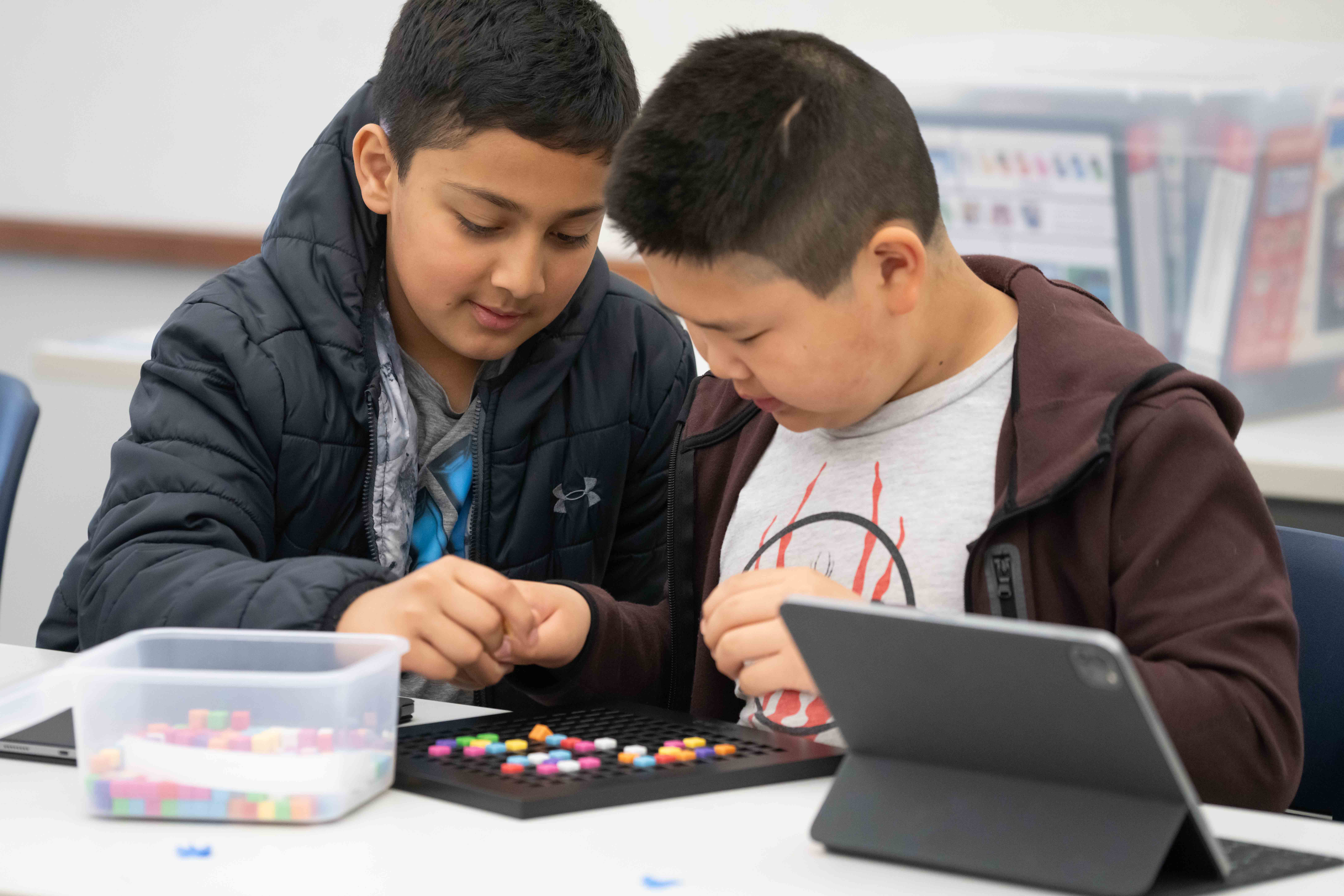 Two students working together on a colorful bead pegboard